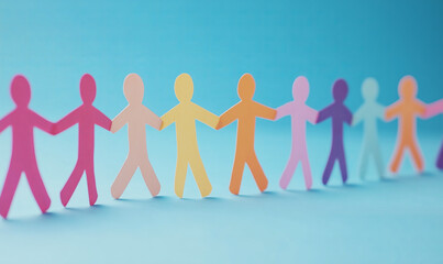 Long chain row of different colorful paper cut out people humans holding each other's hands on blue background, symbol of diversity, teamwork and equality.