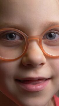 Funny little girl in glasses with eye problem. Vision, child treatment. Toothless cute kid smile