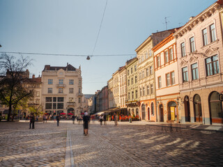 Beautiful view of the central square in Lviv, Ukraine, with historic buildings and pedestrians enjoying a sunny day. Perfect for travel promotions, cityscape photography, and cultural exploration