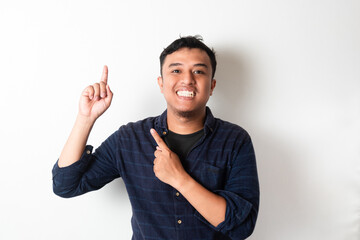 Fototapeta premium Adult Asian man looking at camera with happy expression while pointing up with two finger