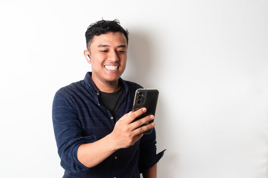 Handsome Asian man listening music using mobile phone and wireless headset