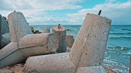 Sea Waves Hitting Shore with Splashing on Heavy Concrete Tetrapod Coastal Defense Structure Seawall Embankment