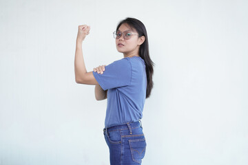 Excited Asian woman proudly lifts her arms, flexing her muscles with a big smile