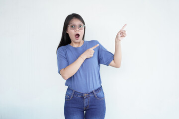 Beautiful Asian woman looks shocked, with a 'wow' expression, pointing to the side with her...