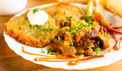 Potato pancakes with grilled beef dish on a white plate