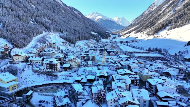 Ischgl, Austria, Europe: Aerial view of ski resort in snowy Tyrolean Alps. Charming village landscape with chalets and hotels surrounded by snow-capped peaks, sunny day, clear blue sky
