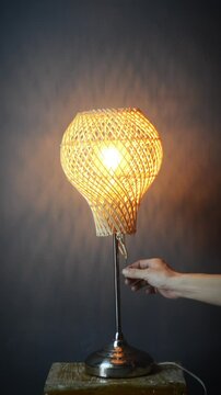 The standing lamp table lamp is turned on and off with a hand switch with a yellow light bulb on a gray and dark background Potrait