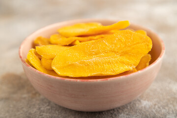 Dried Mango in ceramic bowl on brown concrete. Side view, selective focus
