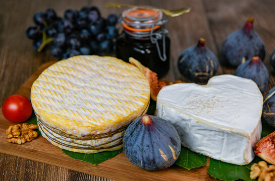 Selection of French cheeses from Normandy, AOP, Livarot, Neufchatel, Pont l'eveque, Rye bread, figs, walnuts, grapes, elderberry gelee. High quality photo