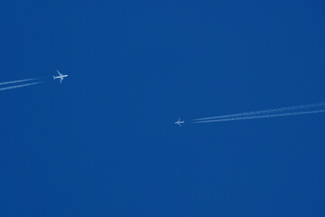 Two airplanes in the blue sky with contrails, closeup of photo. Airplane trail in the blue sky
