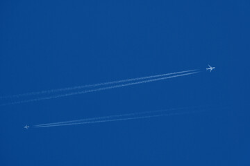 Two airplanes in the blue sky with contrails, closeup of photo. Airplane trail in the blue sky