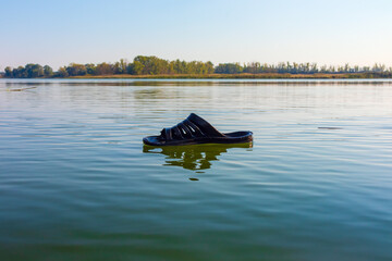 Rubber slipper foam floats on the surface of the water of a river or lake on a sunny day