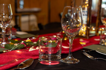 A beautifully decorated wedding hall with red tablecloths, illuminated glass bottles, and elegant lighting creating a warm, festive atmosphere