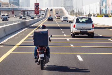 Dubai. Man on a motorcycle for online delivery. Food delivery. UAE. vertical