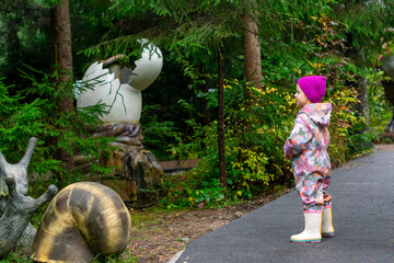 Little girl walks in a dinosaur park