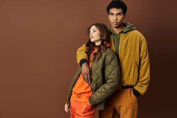 A stylish couple showcases their trendy autumn outfits in rich, warm colors that pop.