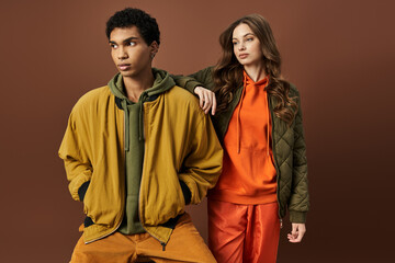 A fashionable young couple poses together, showcasing vibrant autumn attire with confidence.