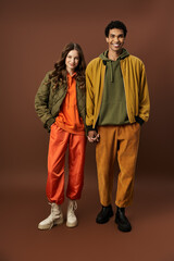 A stylish couple showcases their autumn fashion choices in lively colors and cozy outfits.