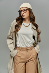 Young woman in elegant autumn attire posing on gray backdrop.