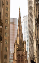 Campanario g&oacute;tico rodeado de los altos rascacielos del barrio financiero, New York, USA. La iglesia episcopal de Trinity Church en Broadway en el sur de Manhattan. 2019.