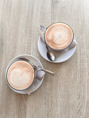Two cups of frothy coffee on the table.