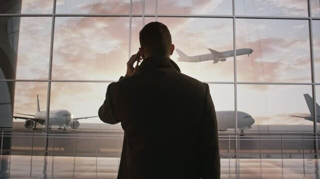 A Man Standing In Front Of A Window Talking On A Cell Phone Airport Advertising Photography Business Travel