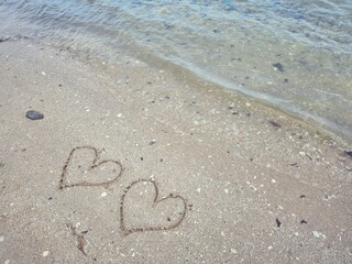 Two hearts drawn on sand beach