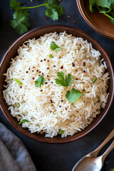 Bowl of fluffy white rice, garnished with herbs.