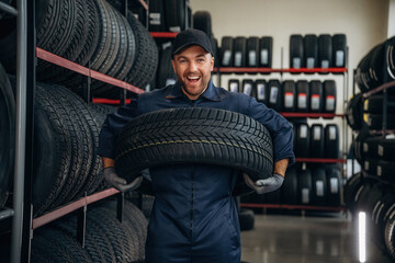 Holding the wheel. Man worker is maintenance station with tires