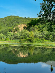 Unique water spring and natural phenomenon Blue Eye (Syri i Kalter) in Muzine, Albania. Crystal-clear blue lake reflecting surrounded by lush greenery and mountains. Peaceful enchanting atmosphere