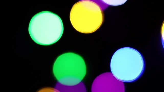Una toma de cerca de varias luces de colores en forma de c&iacute;rculos en movimiento en la oscuridad. Desenfoque