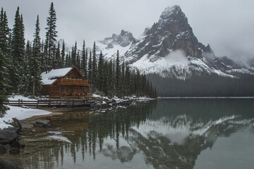 Fototapeta premium Stunning Winter Wonderland Mountain Log Cabin Surrounded by Snowy Trees and Majestic Landscape in a Peaceful Remote Forest