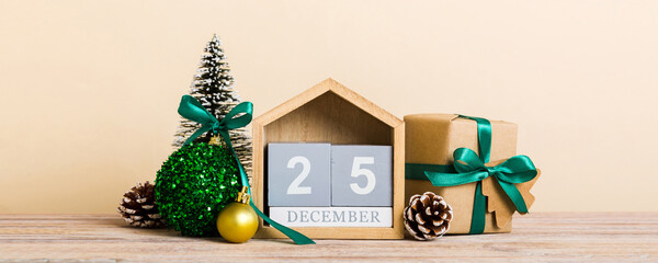 25 december. Christmas composition on colored background with a wooden calendar, with a gift box, toys, bauble copy space