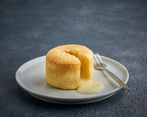 White chocolate fondant or lava cake dessert in a plate, on a dark blue background. Copy space, close-up view. 