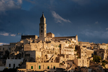 Obraz premium Exploring the ancient sassi of Matera under dramatic clouds at sunset in Puglia, Italy