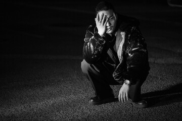 A young Korean man is squatting. Black and white photo
