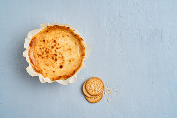 Creamy cheesecake with a biscuit base. Blue background with space for text. Top view, horizontal. Selective focus.