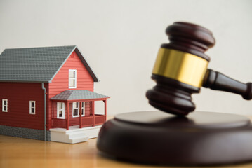 Hammer judge gavel and house model on table with white wall background. Foreclosure, bankruptcy, legal concept. Person is unable to reply outstanding debts or obligations, stops mortgage payment.