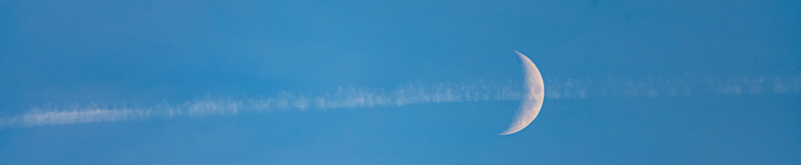 quartier de Lune travers&eacute;e par la fum&eacute;e d'un avion