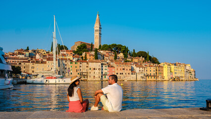 A couple enjoys a peaceful evening by the waterfront as the sun sets in Rovinj, Croatia