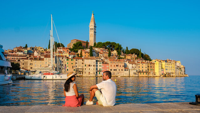 A couple enjoys a peaceful evening by the waterfront as the sun sets in Rovinj, Croatia