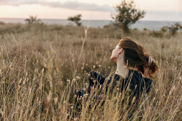 Woman in deep contemplation as her hair dances in the wind among the golden grass at sunset