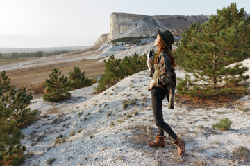 Woman standing on hill admiring majestic mountain and lush valley with pine trees in background