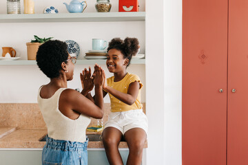 Happy little girl playing a hand clapping game with her mother at home