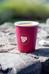 paper cup on stone against blurred green background of mountains