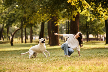 Obraz premium A young woman dressed for autumn enjoys a playful moment with her dog in a beautiful park.