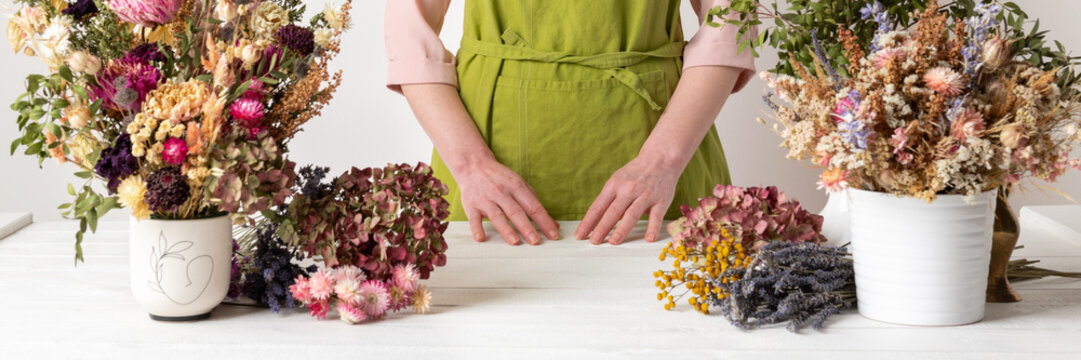 Dried flowers. Female florist arranging dried flowers into a beautiful bouquet. Sustainable floristry. Creating home decor with dried flowers.