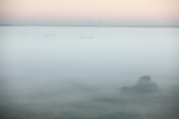 Electric towers in foggy morning landscape