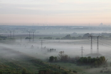 Foggy morning landscape with electric pylons