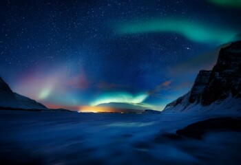 Fototapeta premium A night sky filled with stars and vibrant aurora borealis reflected on a frozen lake, with silhouetted mountain peaks in the background.